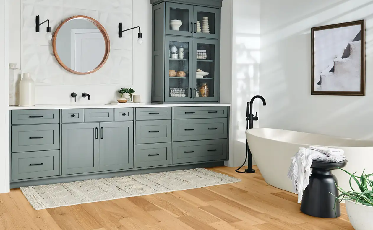 hardwood flooring in bathroom with green cabinetry.