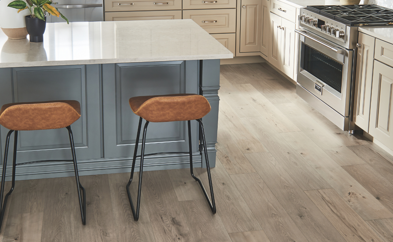 Laminate flooring in a kitchen with a kitchen island and 2 barstools